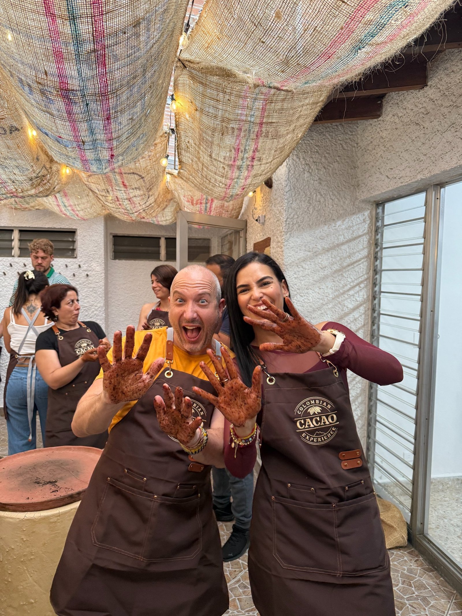 Smiling tourists show chocolate-covered hands during a Colombian cacao experience workshop.